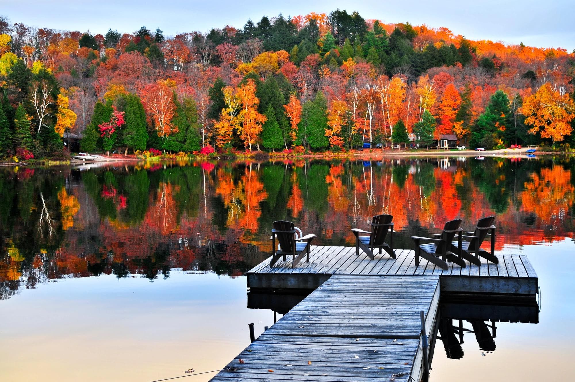 Quai et chaises longues au bord du lac avec forêt automnale