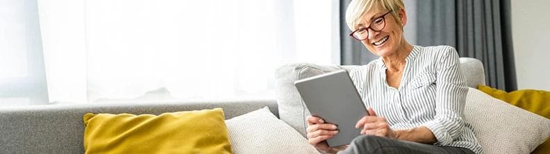 femme lisant sur iPad allongée sur le divan