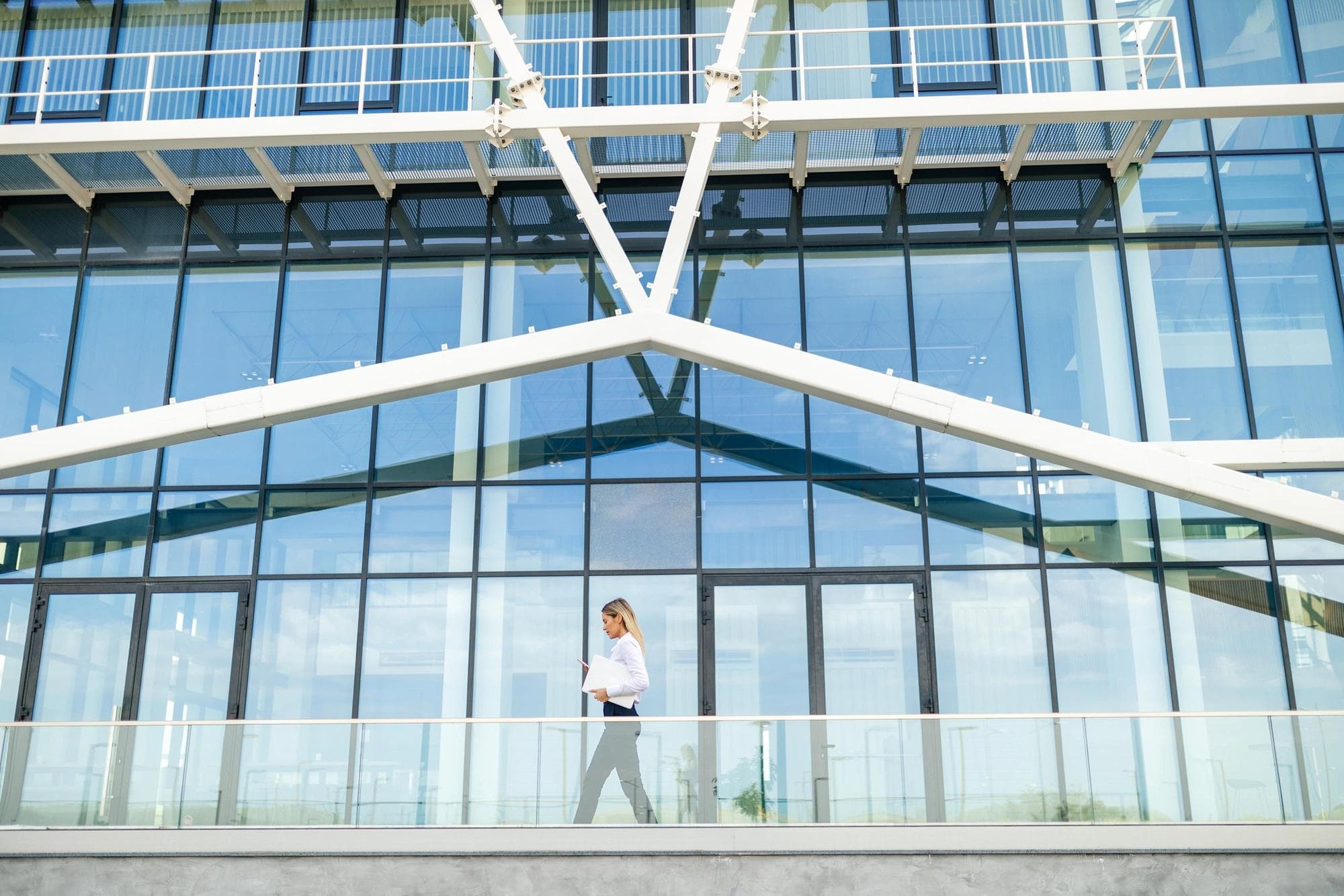 femme marchant devant un immeuble de bureaux moderne