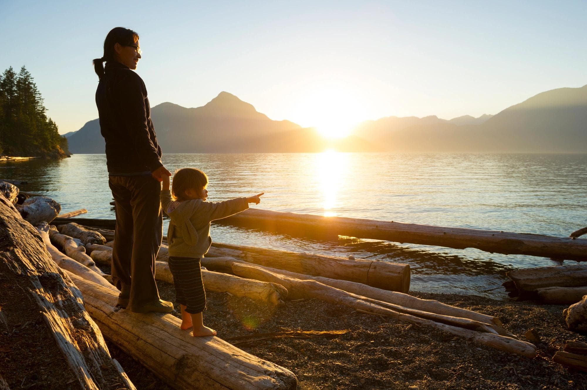 Une maman tient la main de son enfant sur la plage.